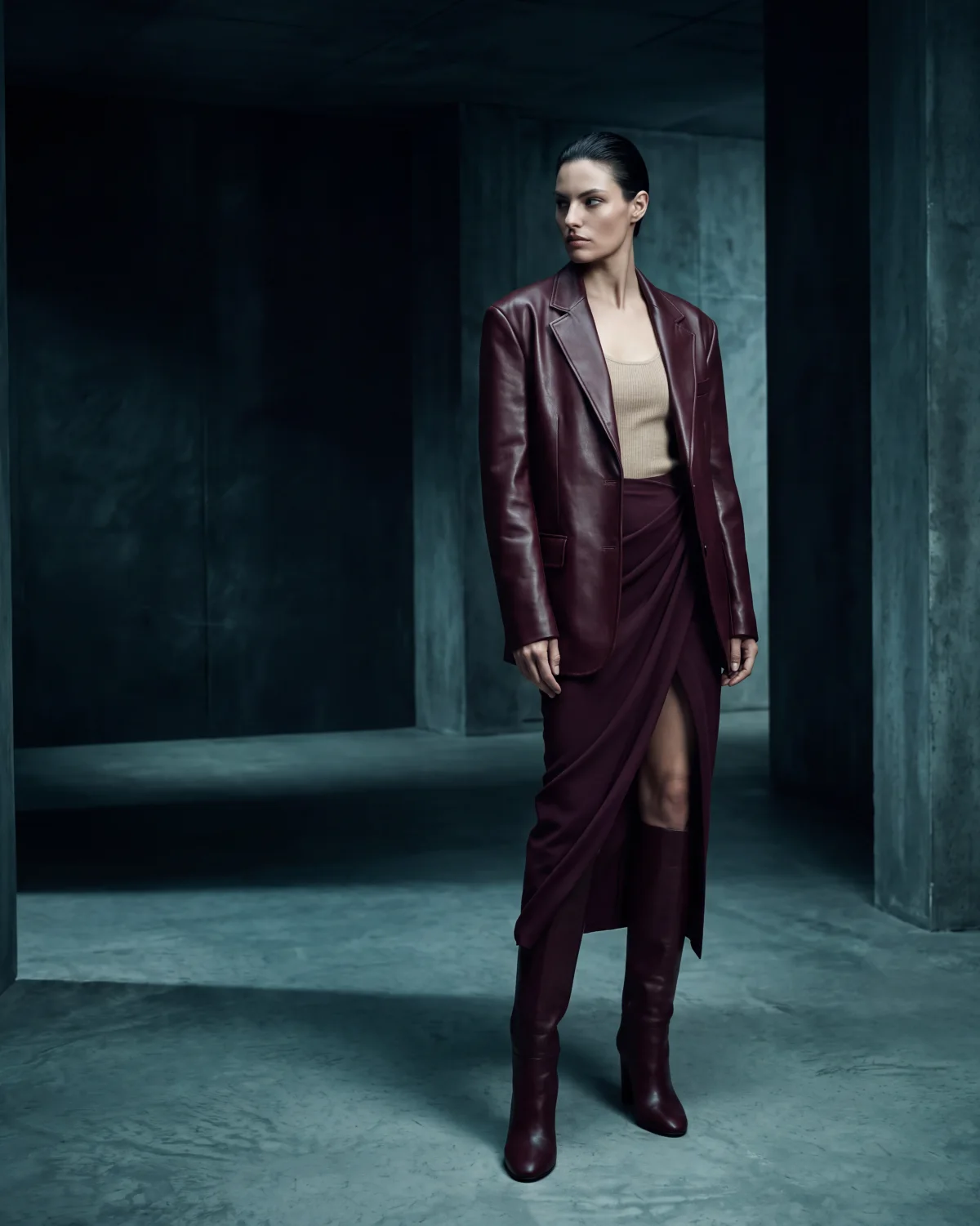 Editorial campaign image of the burgundy look in a dark architectural setting