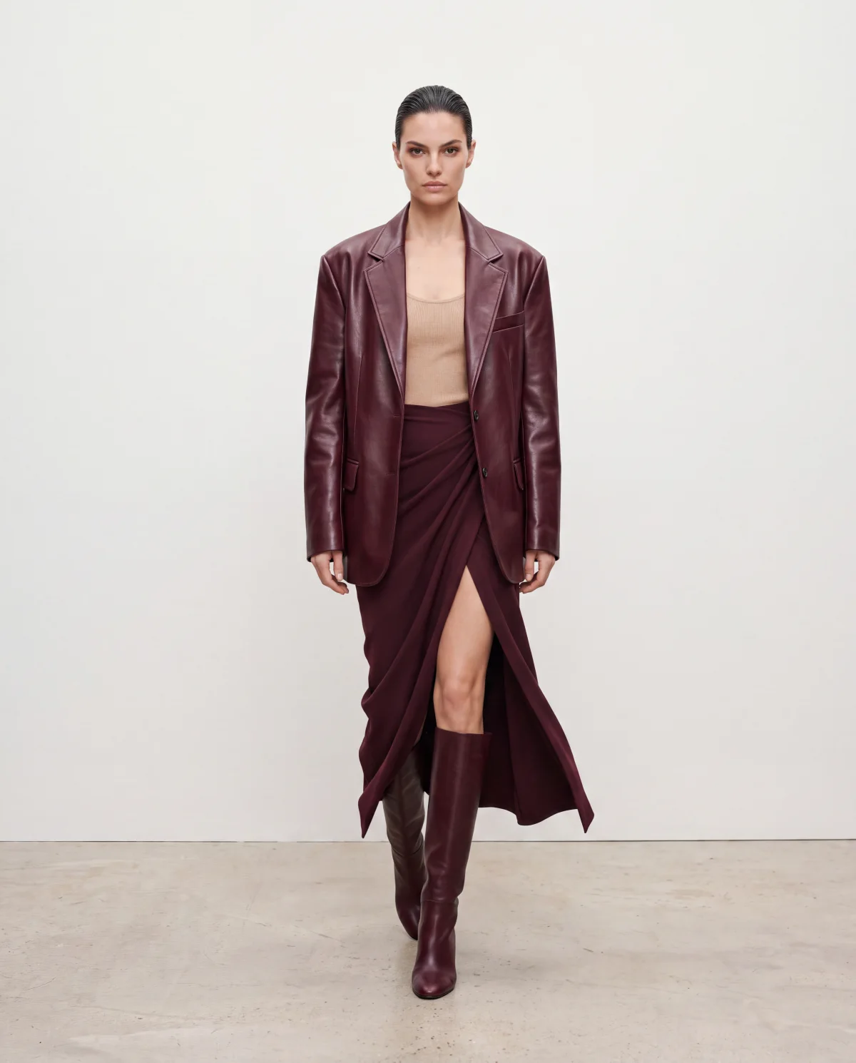 On-model e-commerce image of the burgundy leather blazer, draped skirt and boots